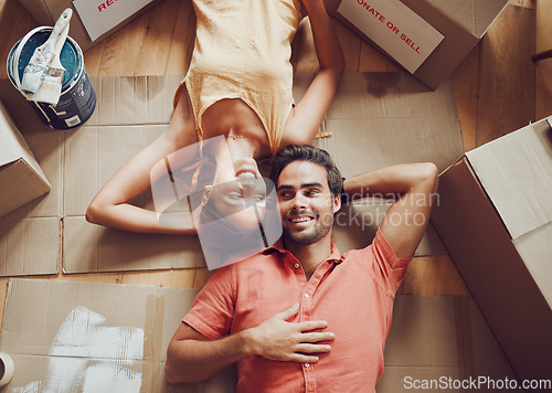 Image of Home improvement, renovation and remodeling with a young couple lying on the floor together at home from above. Man and woman homeowners moving house, painting and unpacking boxes or packages