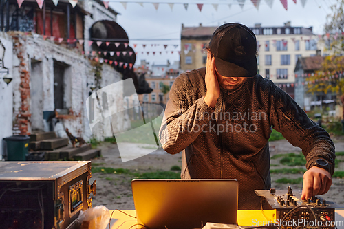 Image of A young man is entertaining a group of friends in the backyard of his house, becoming their DJ and playing music in a casual outdoor gathering