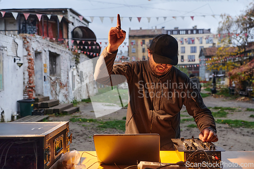 Image of A young man is entertaining a group of friends in the backyard of his house, becoming their DJ and playing music in a casual outdoor gathering