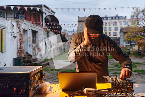 Image of A young man is entertaining a group of friends in the backyard of his house, becoming their DJ and playing music in a casual outdoor gathering