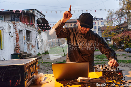 Image of A young man is entertaining a group of friends in the backyard of his house, becoming their DJ and playing music in a casual outdoor gathering