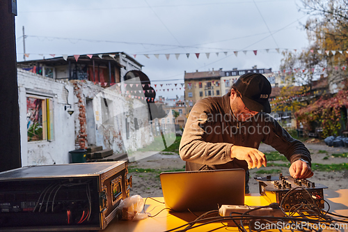 Image of A young man is entertaining a group of friends in the backyard of his house, becoming their DJ and playing music in a casual outdoor gathering