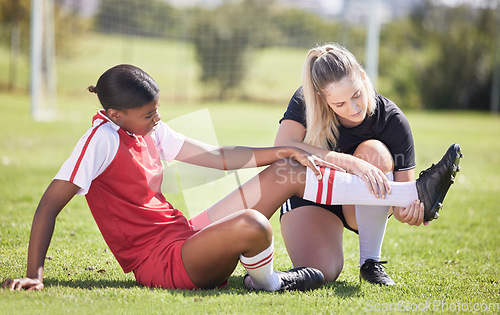 Image of Soccer, sports and injury of a female player suffering with sore leg, foot or ankle on the field. Painful, hurt and discomfort woman getting her pain checked out by athletic trainer on the pitch.