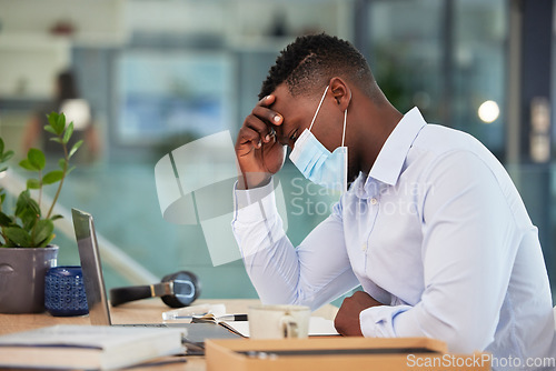 Image of Business man tired, sick and ill with covid at work sitting at a desk and wearing a mask with a headache. A sad, worried and unhappy male employee suffering from covid19 symptoms at the workplace