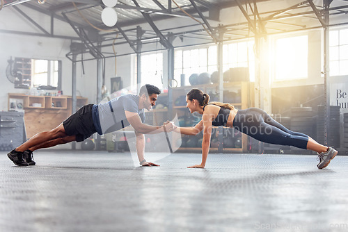 Image of Active couple holding hands for support in pushup, plank and balance training during fitness, workout and exercise in a gym. Sporty, strong and fit athletes helping with bodyweight wellness challenge