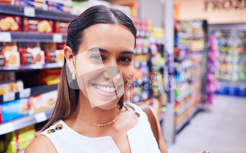 Image of Shopping, groceries and consumerism with a young woman in a grocery store, retail shop or supermarket aisle. Closeup portrait of a female standing with packed shelves of consumables in the background