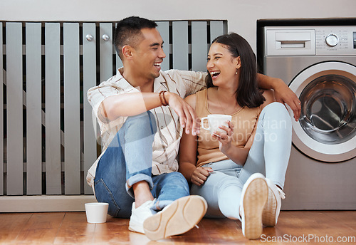 Image of Happy, carefree and romantic couple bonding, laughing and having fun while sitting on the floor. Loving cheerful husband and wife having a cup of coffee, talking and relaxing in the kitchen at home