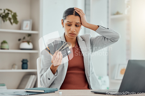 Image of Financial stress, concerned and frustrated woman holding bank cards in her hand at her desk. Business female worried about economic decisions, credit interest or loan and debt in money crisis.