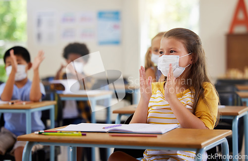 Image of Safety, compliance and education in classroom at school with students wearing masks during corona pandemic. Young learners clapping, excited and attentive during and educational lesson on hygiene