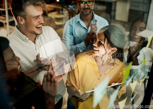 Image of Successful business team clapping and cheering after planning a project on a glass wall in a office. Group of smiling businesspeople sharing ideas and strategies together in a creative startup agency