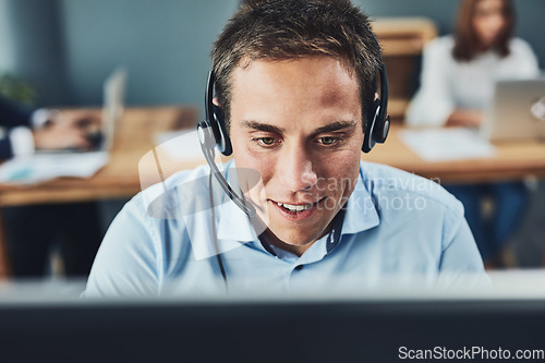 Image of Closeup of a young male call center agent consulting and giving support while working in a busy office. Face of a man and helpdesk worker or phone operator having a conversation