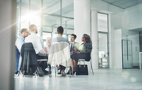 Image of Group of diverse coworkers talking together while sitting in a circle in an office. Employees having a team business meeting discussion for counseling or support group at a corporate workplace.