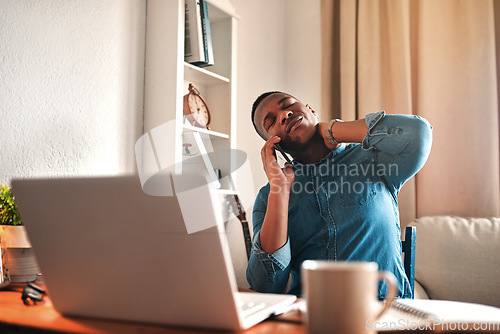 Image of Tired business man with neck pain on a laptop and phone call, looking stressed and stretching bad, strained muscle or sore back. Stressed, multitasking guy having a difficult time working from home