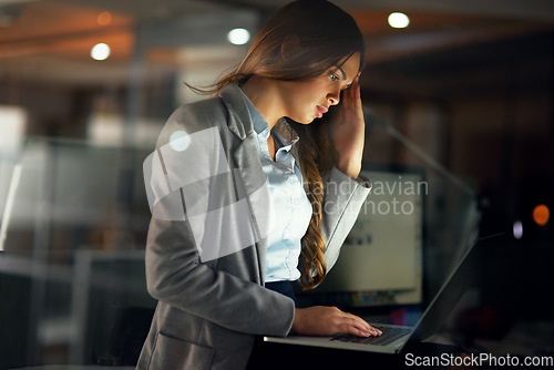 Image of Stressed, worried and tired female entrepreneur typing on a laptop and working overtime late at night. Frustrated and overworked young businesswoman with a headache doing a project with a deadline