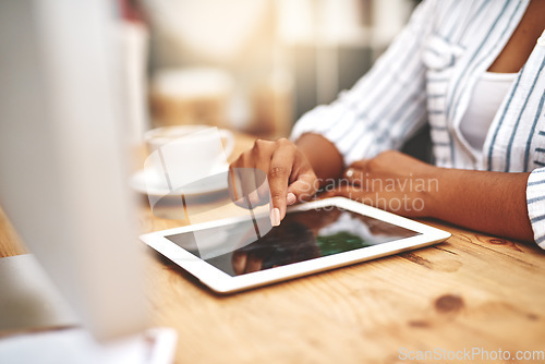 Image of Female african hand using a tablet at a desk doing office work. Closeup of a professional woman browsing on social media while having a cup of tea or coffee. Businesswoman doing research online.