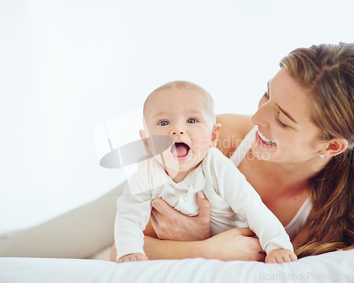 Image of Loving mother and baby bonding at home, playing while relaxing on a bed together. Happy parent being affectionate with her newborn son, embracing him and sharing precious moments of parenthood