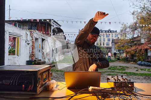 Image of A young man is entertaining a group of friends in the backyard of his house, becoming their DJ and playing music in a casual outdoor gathering