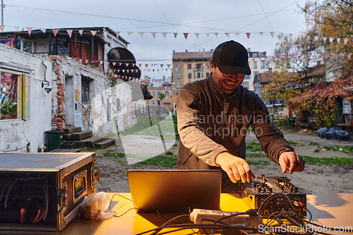 Image of A young man is entertaining a group of friends in the backyard of his house, becoming their DJ and playing music in a casual outdoor gathering