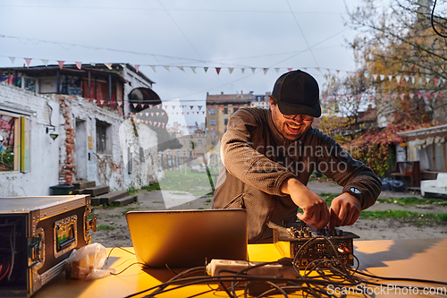 Image of A young man is entertaining a group of friends in the backyard of his house, becoming their DJ and playing music in a casual outdoor gathering