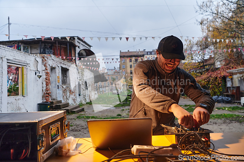 Image of A young man is entertaining a group of friends in the backyard of his house, becoming their DJ and playing music in a casual outdoor gathering