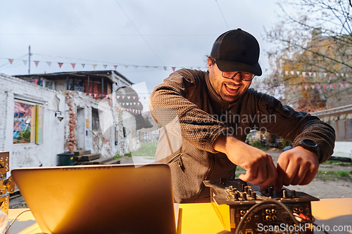 Image of A young man is entertaining a group of friends in the backyard of his house, becoming their DJ and playing music in a casual outdoor gathering