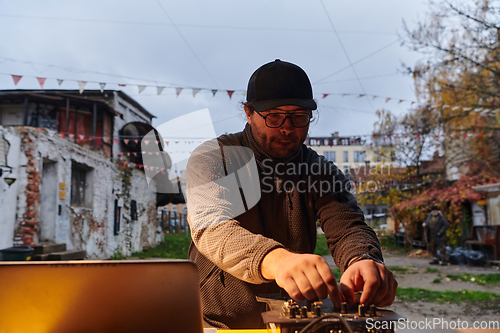 Image of A young man is entertaining a group of friends in the backyard of his house, becoming their DJ and playing music in a casual outdoor gathering