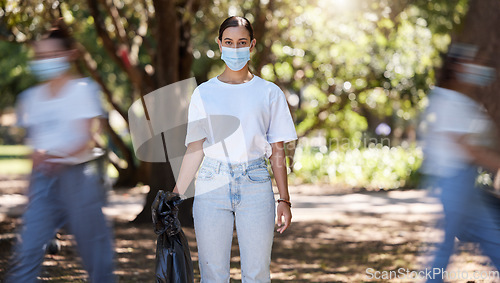 Image of Female wearing covid mask cleaning the park for a clean, hygiene and safe green outdoor environment. Community service, volunteers or activist workers with rubbish, trash and garbage in a plastic bag