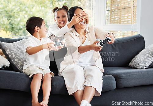 Image of Family, video games and cheating little girl covering her mothers eyes to let her brother win on the couch at home. Entertainment, joystick and having fun while enjoying a bonding activity with kids