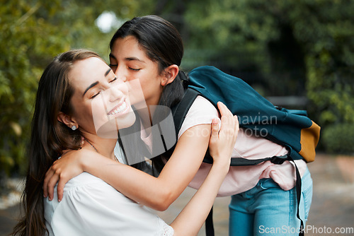 Image of Daughter, hugging and giving a kiss to her mom before going into school. Happy parent has strong relationship and cute bond with her child. Young girl shows love, affection and care for her mother.