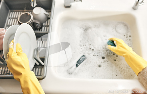 Image of Housewife, maid or cleaner hands washing dishes in the kitchen sink for home hygiene, wearing rubber gloves. Contact us for cleaning solutions or professional domestic household chores service.