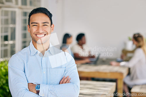 Image of Motivated, confident and happy business man standing arms crossed in the boardroom for a meeting with his colleagues in the background. Portrait of a male with a mindset of innovation and growth