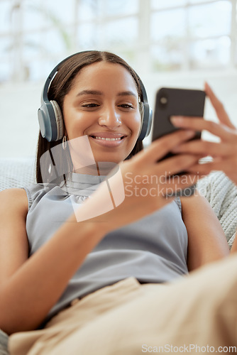 Image of Happy, smiling woman listening and browsing music on her phone during a break at work. Business woman enjoying some free alone time at the office texting and catching up on her social media.