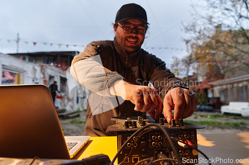 Image of A young man is entertaining a group of friends in the backyard of his house, becoming their DJ and playing music in a casual outdoor gathering