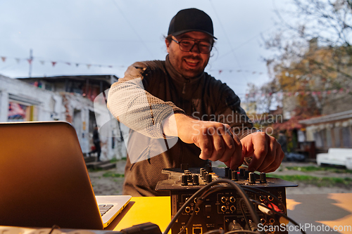 Image of A young man is entertaining a group of friends in the backyard of his house, becoming their DJ and playing music in a casual outdoor gathering