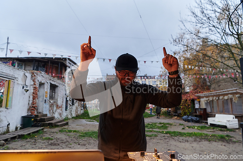 Image of A young man is entertaining a group of friends in the backyard of his house, becoming their DJ and playing music in a casual outdoor gathering