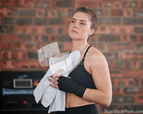 Image of Sweaty, active sports woman taking break from a training workout session, exercising or boxing in gym with sportswear. Strong, healthy and athletic woman wiping sweat with towel at a wellness center