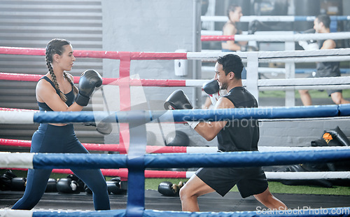 Image of Boxing, training and exercising with a healthy, fit and active female boxer and her male coach or personal trainer in the gym. Workout, fitness and exercise with an athlete and her sports instructor