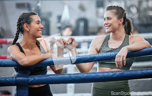 Image of Giving support, motivation and bumping fists after being active, exercising and training in ring. Team of female boxers, fighters or sports athletes standing together in a gym, fitness center or club