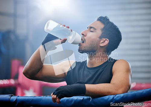 Image of Fit, active and healthy boxer drinking water, on break and staying hydrated in routine workout, training or boxing ring exercise. Sporty, athletic or strong man after kickboxing fight or sports match