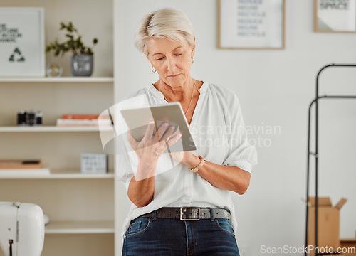 Image of Senior businesswoman, manager or designer reply, responding or sending notification of online orders from handheld tablet. Old clothing producer or business owner serious searching the web in studio.