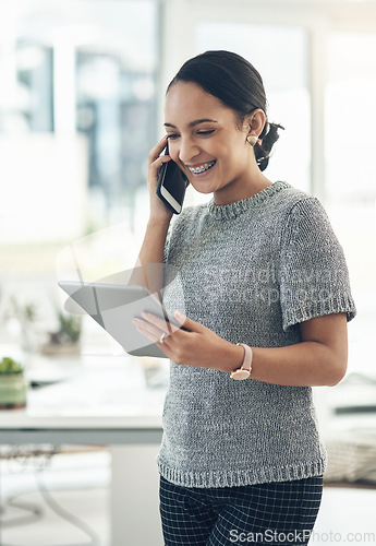 Image of Professional smiling businesswoman talking on phone call with client in modern office. Young design employee working on appointment booking on tablet standing in casual startup company