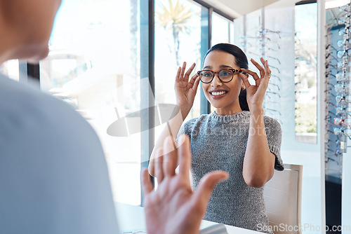 Image of A customer buying, testing or trying on glasses at an optometrist store or shop. Health care eye wear professional picking or selling a pair of new eyeglasses to a young female client or patient.