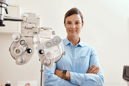 Image of Confident, happy and proud optometrist standing with arms crossed, ready for checkup and preparing equipment in an optometry office. Smiling, successful and wellness portrait of an ophthalmologist