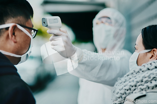 Image of Healthcare worker testing covid temperature for protocol, compliance or countries restrictions at an airport or border. Foreign traveling people with face mask in quarantine or corona virus screening