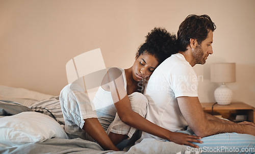 Image of Sad, frustrated and unhappy man and woman hugging after a breakup in their bedroom. Upset, annoyed and depressed male getting support with his wife. Interracial couple cuddling to comfort husband.