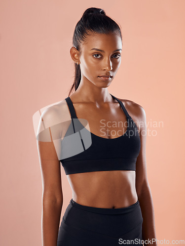 Image of Fit, slim and serious woman feeling confident about her body and health while standing against a pink studio background. Portrait of a sporty and determined woman ready to exercise to stay in shape