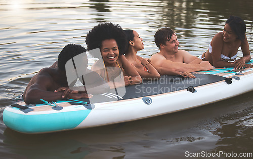 Image of Friends, swimming and summer break with paddle board in a lake, ocean or sea over holiday, vacation or weekend. Diverse group of men and women bonding together, having fun and being playful or social