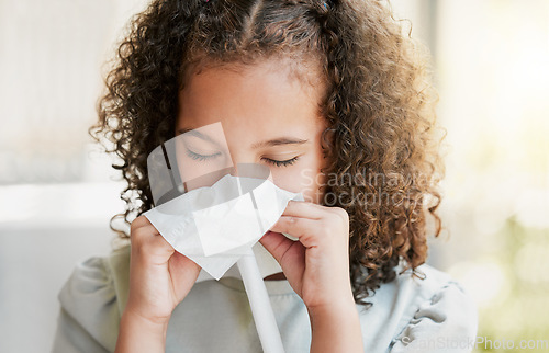 Image of Sick, cleaning nose with tissue and tired girl kid suffering from flu virus, cold or covid at home. Closeup of a young child with a bad allergy or coronavirus sneezing with a sinus headache