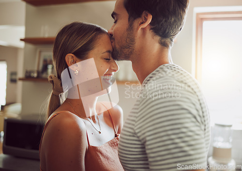 Image of Affectionate, loving and romantic couple in a happy relationship together in the kitchen at home. Man and woman sharing a moment of happiness, romance and bonding with each other in love.