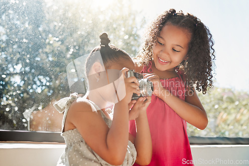 Image of Cute sisters bonding, taking photos on camera at home, smiling while being playful and curious. Little girls playing, having fun together, enjoying their bond and sharing precious childhood moments